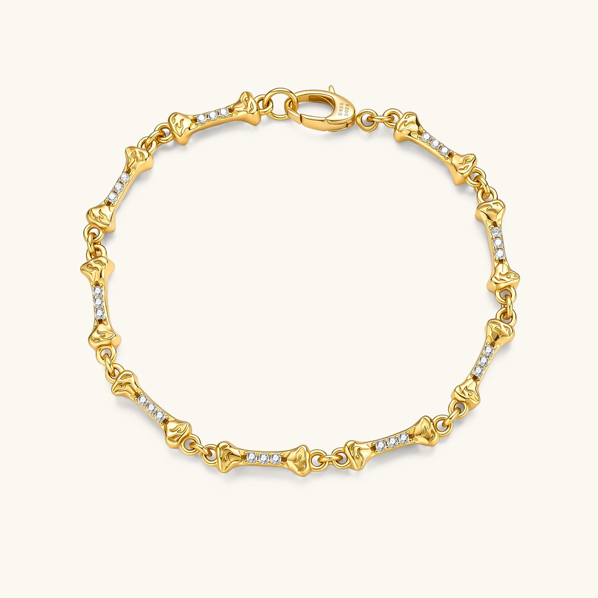 Gold-plated sterling silver bracelet with bone-shaped links, embedded CZ stones, and lobster clasp on light background.