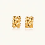 Close-up of gold-plated twisted rope huggie hoop earrings with brushed finish on white background.