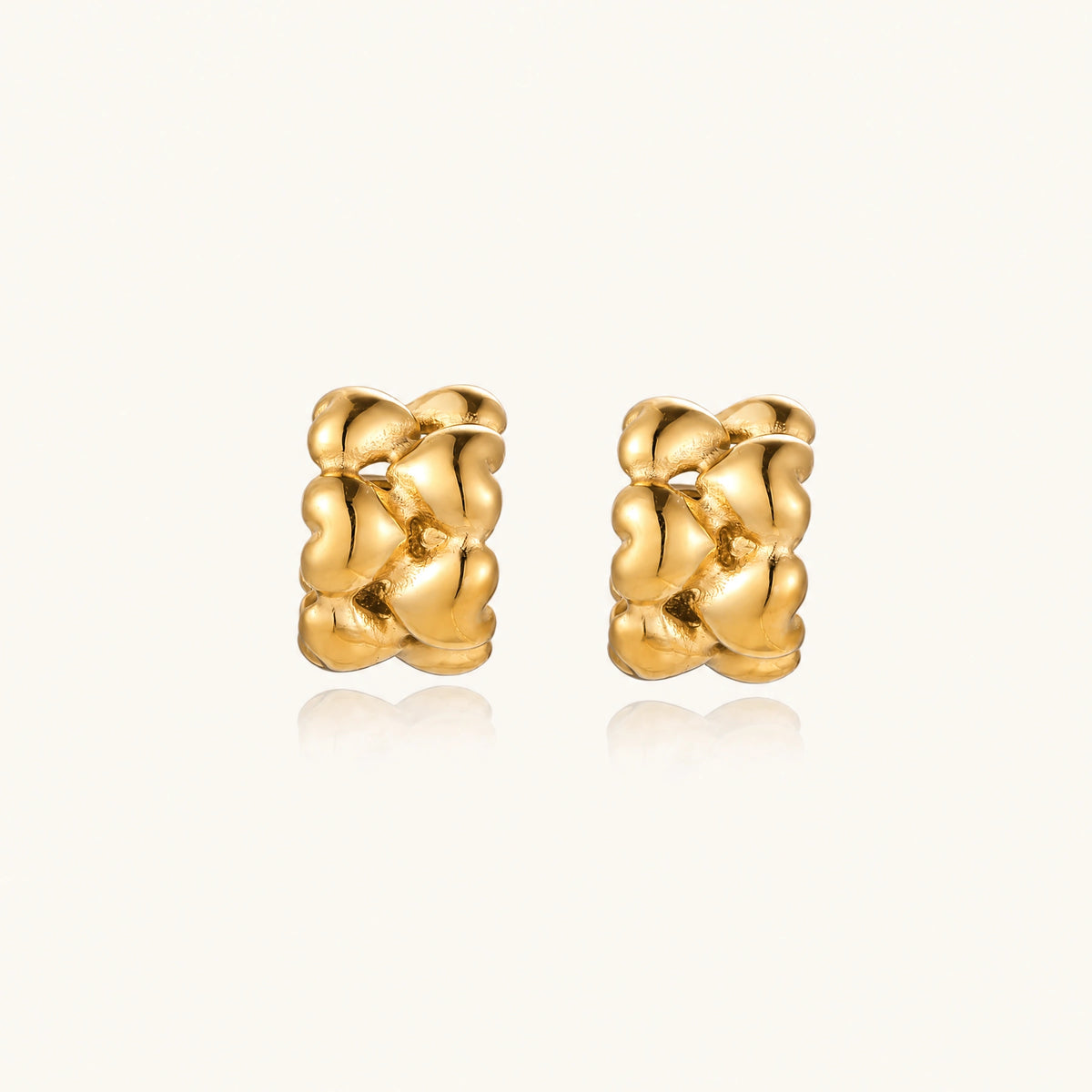 Close-up of gold-plated twisted rope huggie hoop earrings with brushed finish on white background.