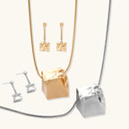 Modern geometric jewelry set featuring crumpled cube pendants in warm gold finish with chain details on beige background.