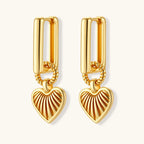 Gold-plated huggie earrings with textured heart charms featuring radiating sunburst patterns on white background.