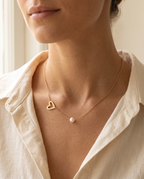 Woman wearing the Pearl Heart Embrace Necklace with open heart and pearl on a fine gold chain