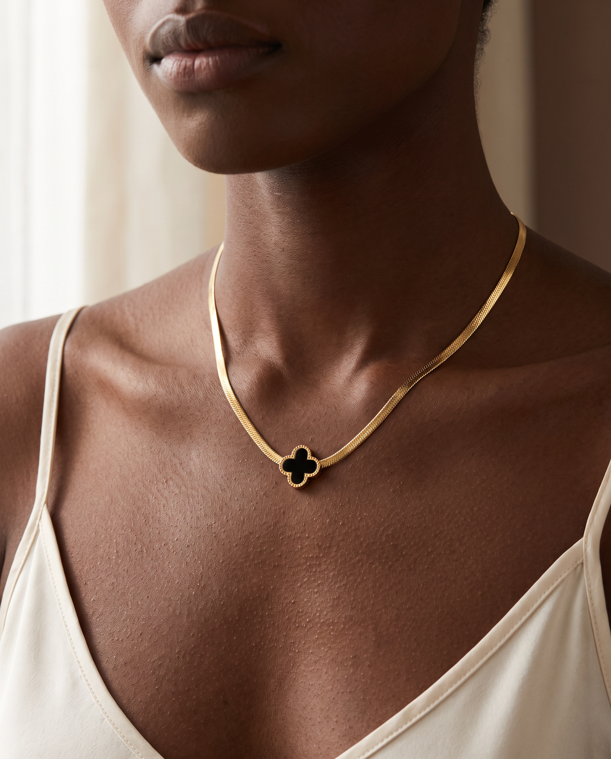 Woman wearing the Lucky Clover Necklace, gold herringbone chain with black enamel clover pendant