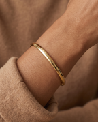 Wrist wearing the Bold Hinge Bangle, polished gold oval bangle