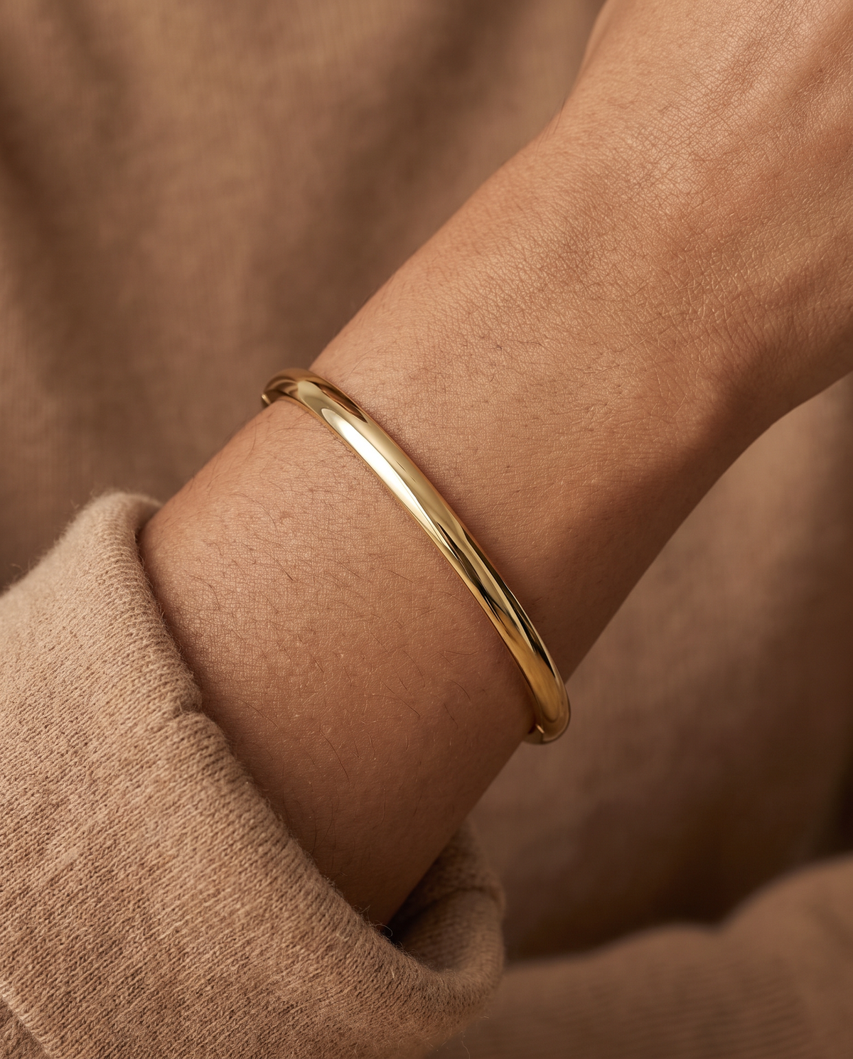 Wrist wearing the Bold Hinge Bangle, polished gold oval bangle
