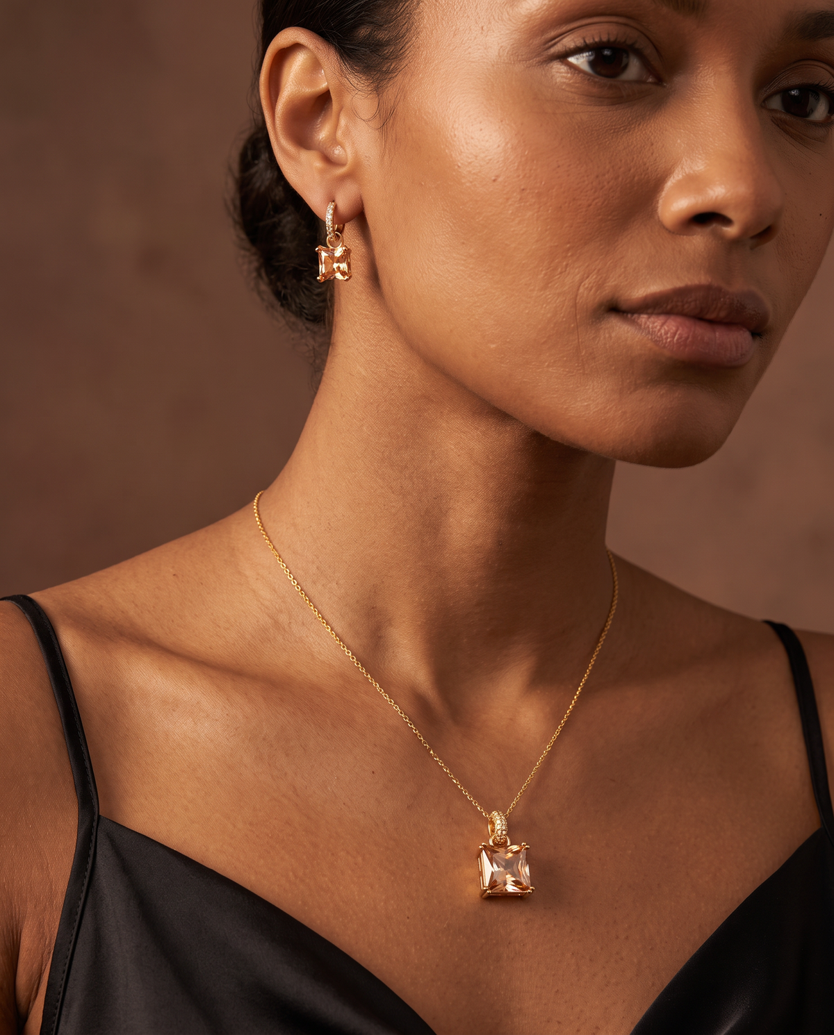 Woman wearing the Golden Hour Geometric Set, champagne square stone necklace and huggies