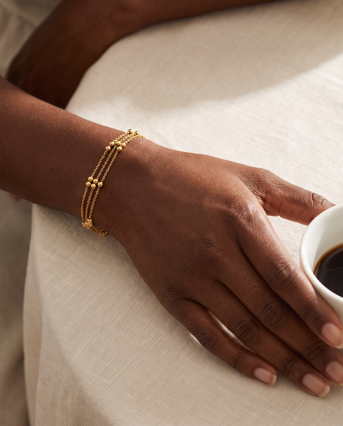 Wrist wearing the Golden Orbit Bracelet, three beaded gold chains